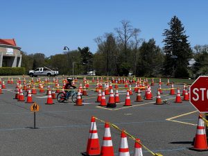 A child biking through a set of orange cones in a parking lot